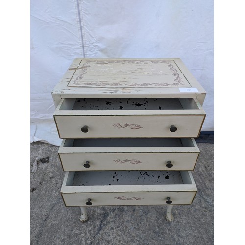 607 - A distressed three drawer bedside table, floral print