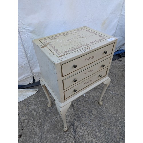 607 - A distressed three drawer bedside table, floral print