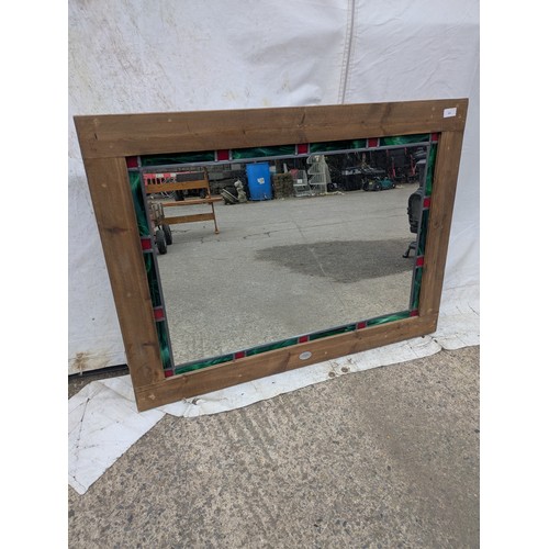 451 - A rustic wall mirror with a coloured leaded glass border and oak frame