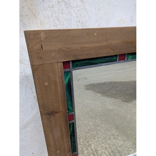 451 - A rustic wall mirror with a coloured leaded glass border and oak frame