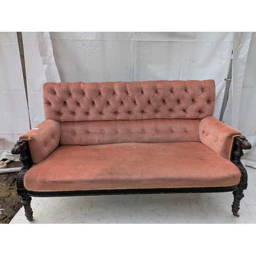 453 - An antique button backed sofa with intricately carved oak arms