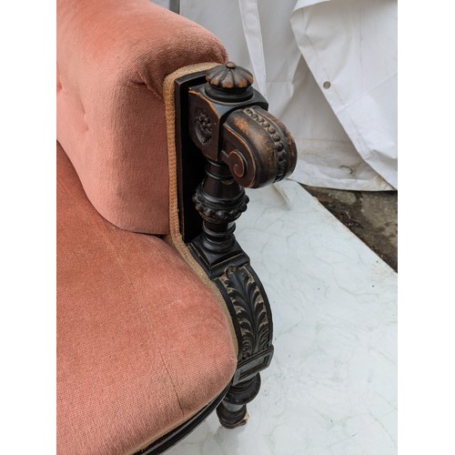 453 - An antique button backed sofa with intricately carved oak arms