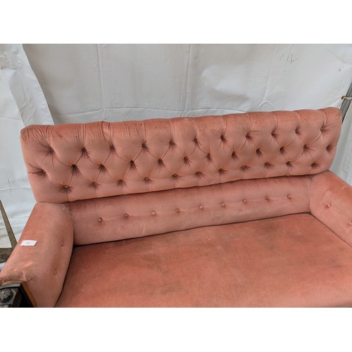 453 - An antique button backed sofa with intricately carved oak arms