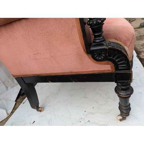 453 - An antique button backed sofa with intricately carved oak arms