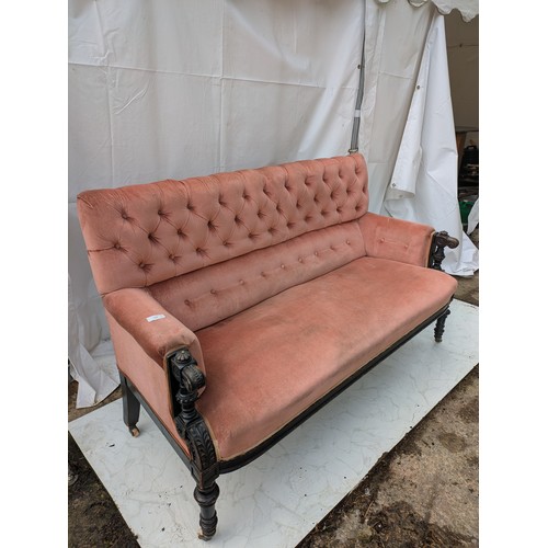 453 - An antique button backed sofa with intricately carved oak arms