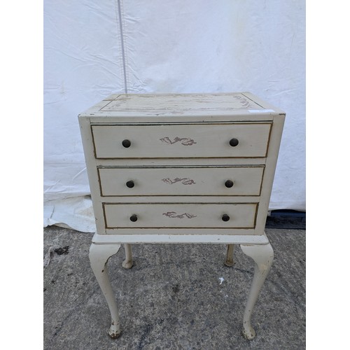 607 - A distressed three drawer bedside table, floral print