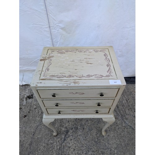 607 - A distressed three drawer bedside table, floral print