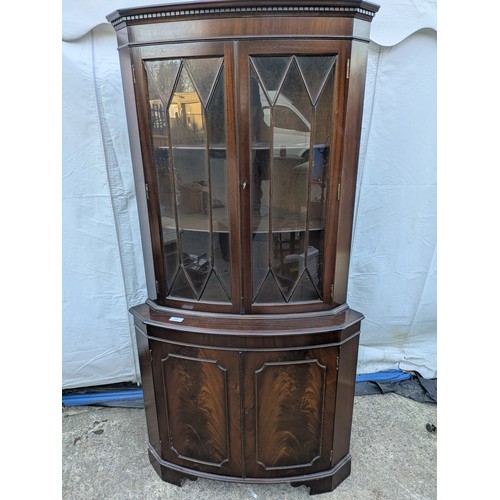 614 - A mahogany veneered corner display glass fronted cabinet.