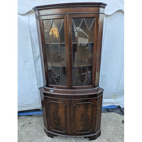 614 - A mahogany veneered corner display glass fronted cabinet.