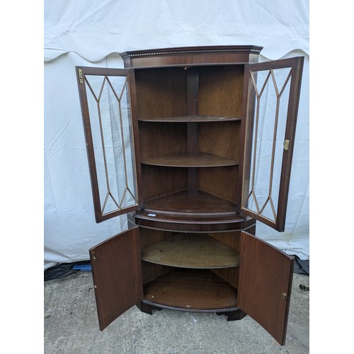 614 - A mahogany veneered corner display glass fronted cabinet.