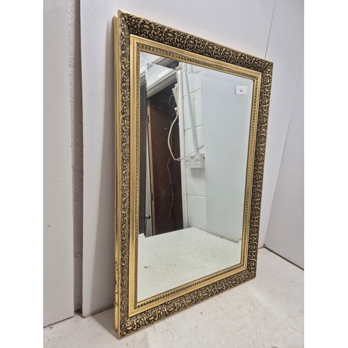 439 - A Bevelled edge wall hanging mirror in a heavily engraved Gold Gilt frame