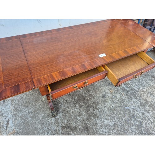28 - A mahogany vaneered drop leaf side table with 2 drawers and lions paw castors