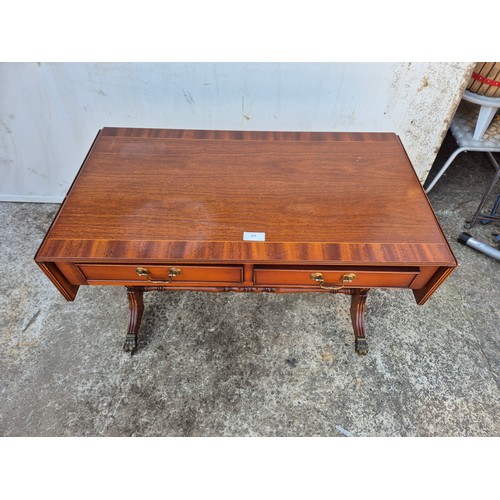 28 - A mahogany vaneered drop leaf side table with 2 drawers and lions paw castors