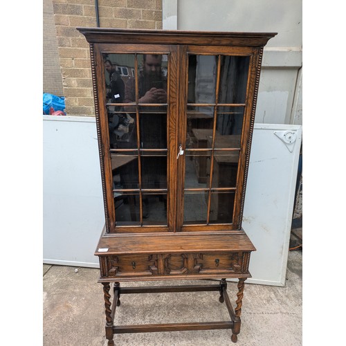 650 - A vintage oak glass fronted display cabinet with underlying drawers - key included