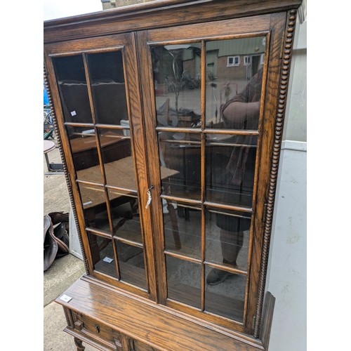 650 - A vintage oak glass fronted display cabinet with underlying drawers - key included