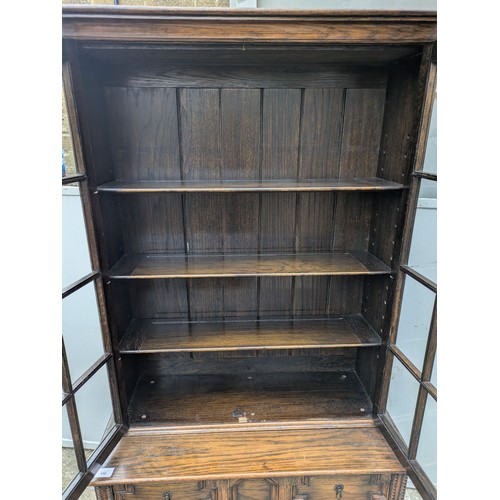 650 - A vintage oak glass fronted display cabinet with underlying drawers - key included