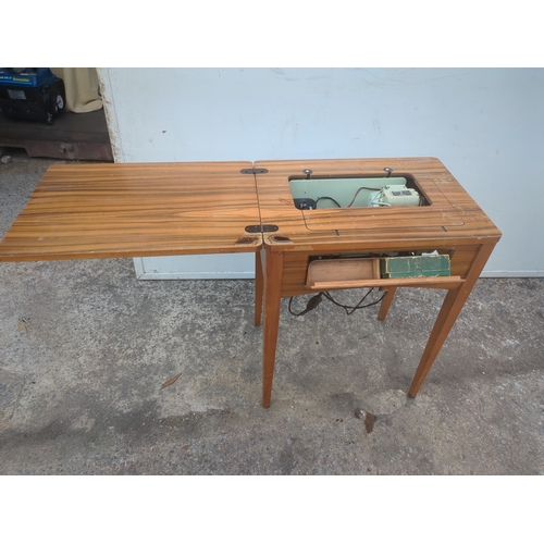 719 - A vintage Singer sewing machine in sewing table