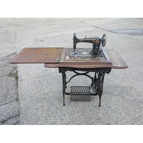 722 - An antique sewing machine in wrought iron table