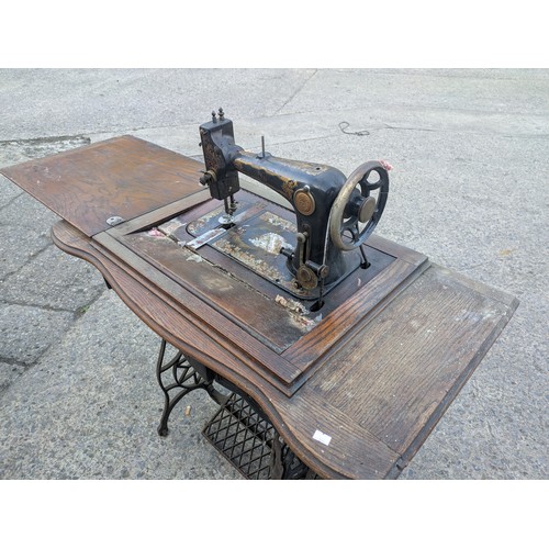 722 - An antique sewing machine in wrought iron table