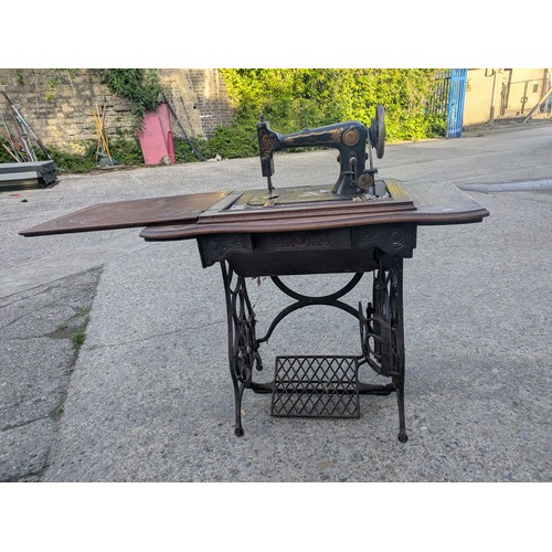 722 - An antique sewing machine in wrought iron table