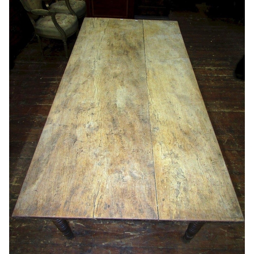 1512 - A 19th century elm farmhouse kitchen table,the plank top raised on four turned tapering bobbin suppo... 