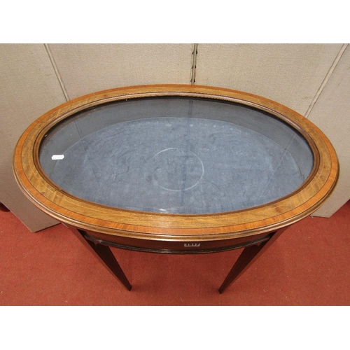 1517 - An Edwardian mahogany vitrine of oval form with plate glass top raised on four square taper supports... 