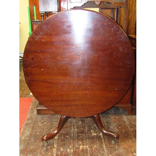 1553 - A large Georgian mahogany snap top table,the circular top 110 cm diameter raised on a vase shaped pi... 