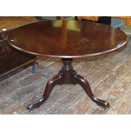 1553 - A large Georgian mahogany snap top table,the circular top 110 cm diameter raised on a vase shaped pi... 