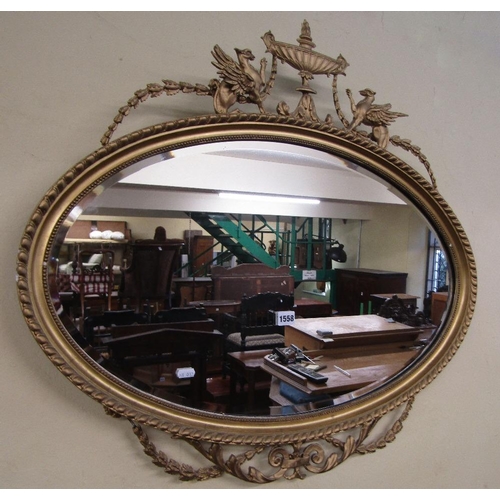 1558 - A Georgian style oval gilt framed wall mirror with bevelled edge plate and moulded outline,with rais... 