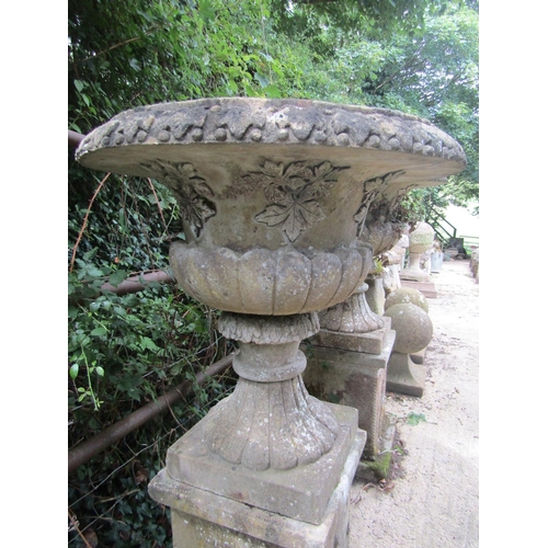 27 - A pair of good quality weathered reconstituted fluted urns raised upon square cut bases, 52