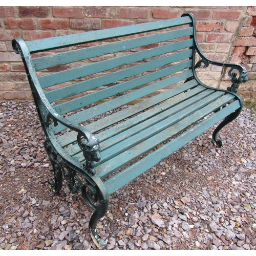 168 - A small cast iron garden bench with lion head detail and timber lathes, painted, 130cm long