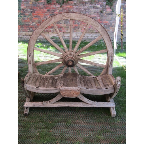 196 - A rustic weathered farmyard seat with wagon wheel back, to seat two, 140cm wide