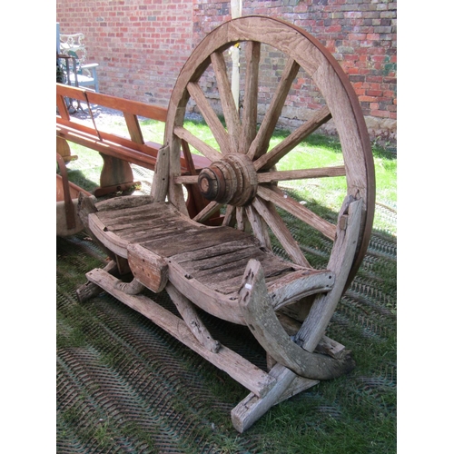 196 - A rustic weathered farmyard seat with wagon wheel back, to seat two, 140cm wide