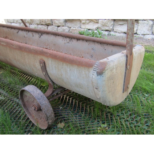 177 - A vintage galvanised iron sheep feeding trough, with central bar and single axle, 275cm long