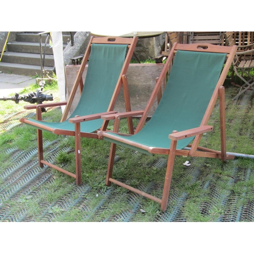 207a - A pair of teak wood folding deck chairs with green canvas seats