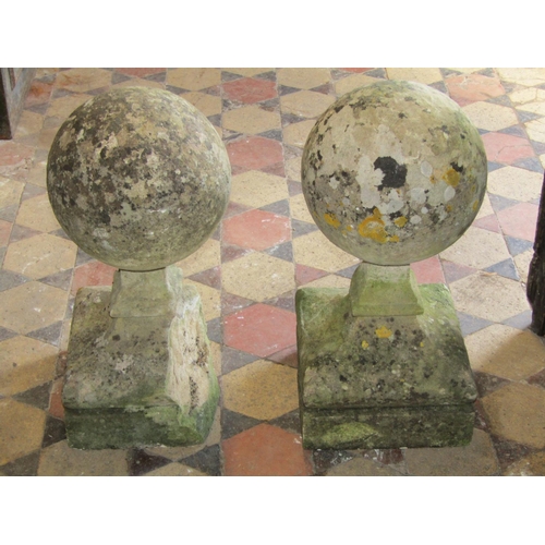 1702 - A pair of antique weathered limestone capitals in the form of balls on waisted square cut supports, ... 