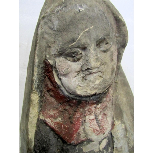 1729 - A weathered natural stone carved figure of an elderly lady wearing a cloak and pleated skirt and aid... 