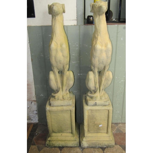 1717 - A pair of contemporary cast composition stone garden ornaments in the form of whippets/hounds, seate... 