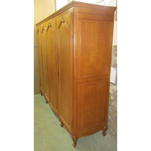 1828 - A light oak armoire enclosed by four full length fielded arched panelled doors over a shaped apron a... 