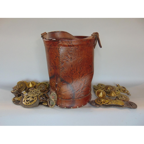 1444 - A studded leather fire bucket containing a large collection of horse brasses