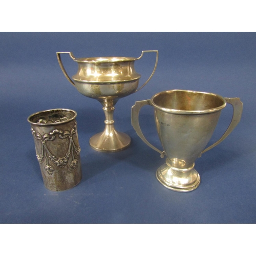 842 - A mixed collection of silver comprising two twin handled trophies and a further bottle sleeve emboss... 