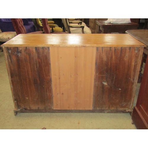 1864 - A Victorian stripped pine dresser fitted with three frieze drawers over a pair of cupboards flanking... 