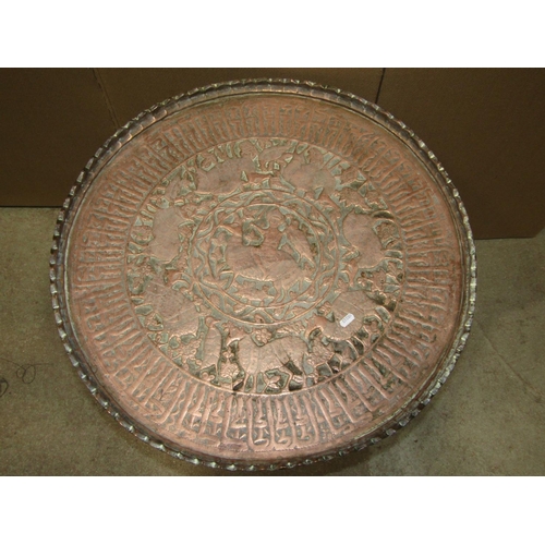 1890 - An Eastern embossed copper circular tray top occasional table raised on a folding ebonised turned st... 