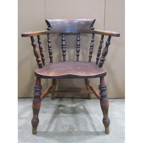 1908 - A Windsor smokers bow elbow chair, principally in elm, with turned spindle back over a saddle shaped... 