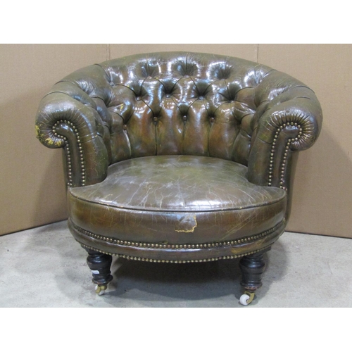 1909 - A late Victorian low green leather, upholstered tub chair with scrolled and buttoned back, raised on... 