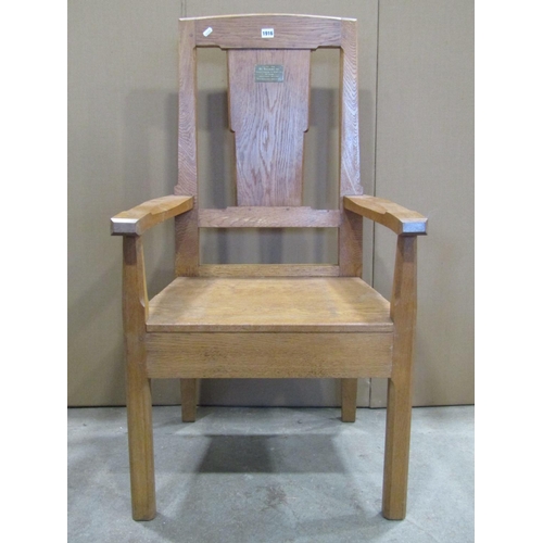 1916 - An oak open armchair with chamferred frame, solid seat, through jointed arms and broad splat, with a... 