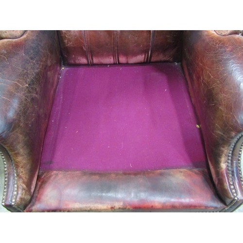 1921 - A Georgian style wing armchair with ox-blood coloured leather upholstery, buttoned back and studded ... 