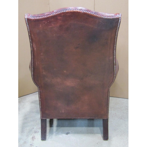 1921 - A Georgian style wing armchair with ox-blood coloured leather upholstery, buttoned back and studded ... 