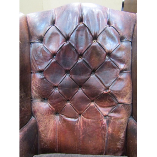 1921 - A Georgian style wing armchair with ox-blood coloured leather upholstery, buttoned back and studded ... 