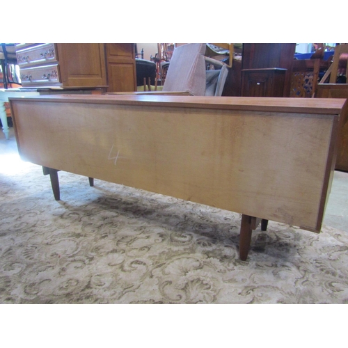 1937 - A long and low retro teak sideboard, partially enclosed by three doors and a tower of three drawers,... 